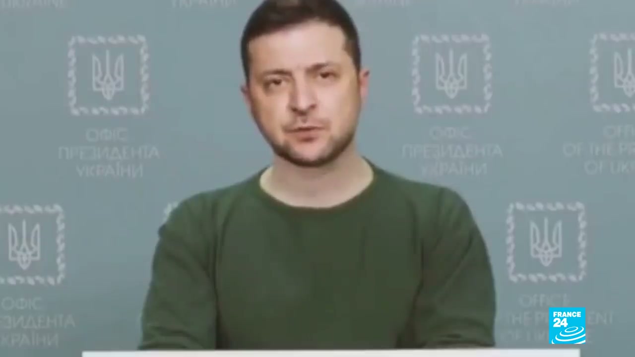 Fotogramma del video falso del marzo 2022: un Volodymyr Zelensky generato, in maglione verde, davanti allo sfondo con gli stemmi dell'Ufficio del Presidente